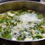 Ein Topf Suppe mit grünem Gemüse.